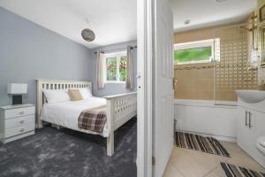 Spacious 5-Bed House in Aylesford في Snodland: غرفة نوم مع سرير وحوض استحمام ومغسلة