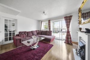a living room with a purple couch and a table at Spacious 5-Bed House in Aylesford in Snodland