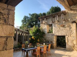 ein Tisch mit Stühlen im Freien und ein Steingebäude in der Unterkunft Country Villa for 18 Pool Cinema Football Pitch in Verteillac