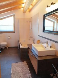 a bathroom with a sink and a tub and a toilet at Wolke 8 in Bernau am Chiemsee