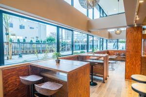 a restaurant with large windows and tables and stools at Wise Owl Hostels River Tokyo in Tokyo