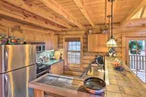 La cuisine est équipée d'un réfrigérateur en acier inoxydable et de placards en bois. dans l'établissement Superb Linville Mountain Cabin with Wraparound Decks, à Linville