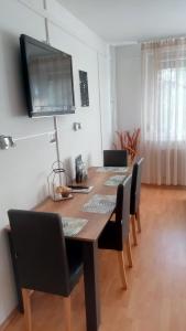 a dining room table with chairs and a television on the wall at merRelax Apartman in Miskolc