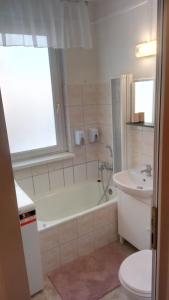 a bathroom with a tub and a toilet and a sink at merRelax Apartman in Miskolc