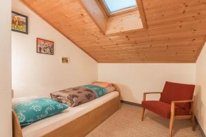 a small bedroom with a bed and a chair at Ladinser Hof Reiterstube in Castelrotto