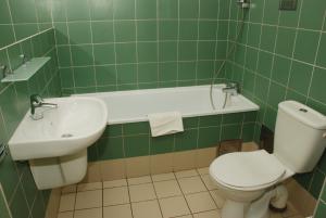 a green tiled bathroom with a toilet and a sink at Ośrodek Innowacja in Zabrze