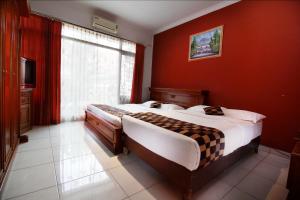 a bedroom with a large bed in a red wall at Fora Guest House Taman Lingkar in Bandung