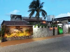 eine Steinmauer mit einer Palme vor einem Gebäude in der Unterkunft Castelo Beach Hotel in Natal
