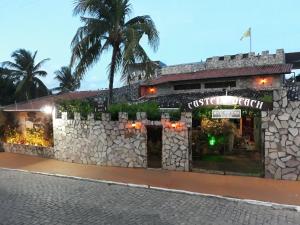 a building with a stone wall and palm trees at Castelo Beach Hotel in Natal