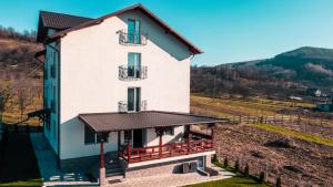 a white house with a balcony on a hill at Casa Dumitru in Ceraşul