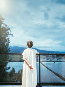 Una mujer con un vestido blanco mirando por la ventana en 三星宿x包棟民宿 享有專屬空間, en Sanxing