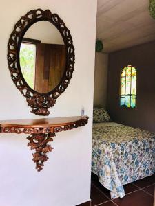 een spiegel aan een muur naast een bed bij Casa do jacques in Conceição da Ibitipoca