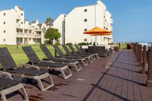 uma fila de cadeiras e um guarda-sol num pátio em Recently renovated! 3 beachfront balconies Beautiful and fully equipped condo em South Padre Island