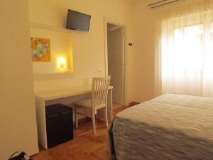 Schlafzimmer mit einem Schreibtisch, einem Bett und einem TV in der Unterkunft Buonarroti Guest House in Rom