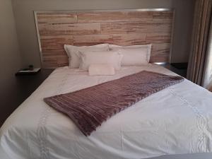 Una gran cama blanca con una manta marrón. en @Home BnB en Maseru