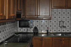 a kitchen with wooden cabinets and a sink and a microwave at Casa Etna in Rascafría