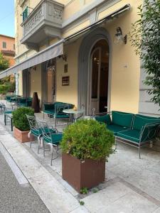 un patio con muebles verdes, mesas y sillas en Hotel Corallo, en Montecatini Terme