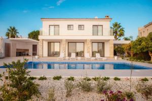 a villa with a swimming pool in front of a house at Villa No 1 - Cap St Georges Resort in Peyia
