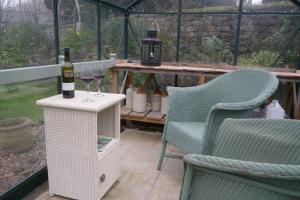 a bottle of wine sitting on a table next to two chairs at Rosedale Cottage in Rosedale Abbey