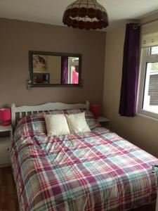 1 dormitorio con 1 cama con manta a cuadros en Upper Lake Chalet Dog and Pet Friendly en Caernarfon