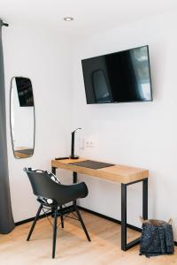 einen Schreibtisch mit Stuhl und einen TV an der Wand in der Unterkunft Ferienwohnungen Schranz GbR in Heppenheim an der Bergstrasse
