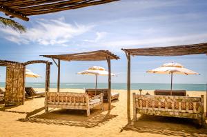 una playa con sombrillas y sillas en la arena en Villas de Gaia Hotel Boutique, en Trancoso