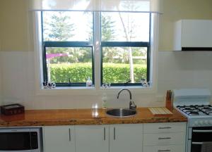 uma cozinha com um lavatório e duas janelas em Channers on Norfolk em Burnt Pine