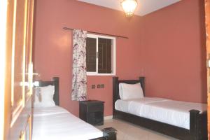 two beds in a room with red walls and a window at Inyan Dakhla Hotel in Dakhla