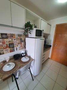 a kitchen with a refrigerator and a table with plates on it at Flat à Beira Lago in Brasilia