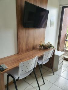 a wooden table with two chairs and a television on a wall at Flat à Beira Lago in Brasilia