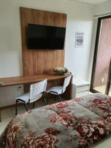 a bedroom with a bed and a desk and a television at Flat à Beira Lago in Brasilia