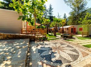 a garden with a stone walkway next to a house at Delle Rose Camping & Glamping Village in Isolabona