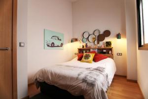 um quarto com uma cama com lençóis brancos e almofadas vermelhas em Las tres Biznagas em Málaga