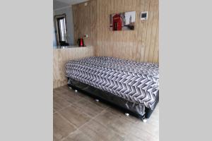 een bed in een kamer met een houten muur bij Cabaña Con Tinajas #2 in Quillón