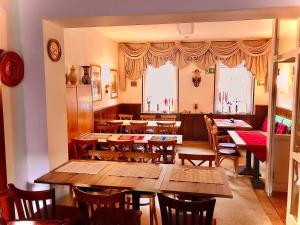a restaurant with wooden tables and chairs and windows at Andefu Hotel am Kantpark in Duisburg