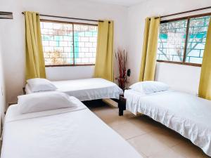 a room with three beds and two windows at Miss Julyn Sweet Home in San Andrés