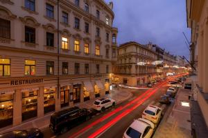 Unesco Prague Apartments في براغ: شارع المدينة بالليل فيه سيارات تقف بالشارع