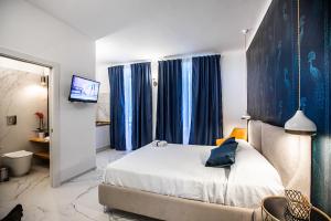 een slaapkamer met een bed met blauwe gordijnen en een televisie bij Domus Vittoria Siracusa in Siracusa