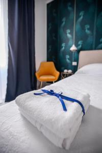 ein weißes Handtuch mit blauem Band auf dem Bett in der Unterkunft Domus Vittoria Siracusa in Syrakus
