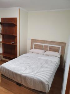 1 dormitorio con cama blanca y estante de madera en Casa Brava, en Alicante