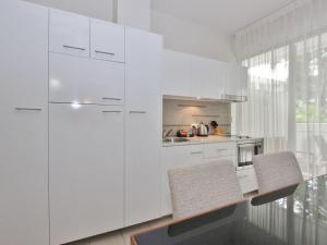 Una cocina blanca con una mesa y dos sillas. en PalmCove DriftAway, en Palm Cove