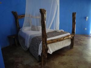 um quarto com uma cama de madeira e um dossel em Casitas El Salitral by Rotamundos em El Pescadero