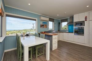 a kitchen with a white table and a large window at Five Palms in Kaikoura