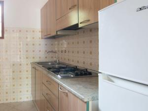 eine Küche mit Holzschränken, einer Spüle und einem Kühlschrank in der Unterkunft Belvilla by OYO Casa Pineta in Rosolina Mare