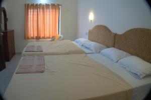 um quarto com 2 camas com lençóis brancos e almofadas em Hotel Sunrise em Kanyakumari