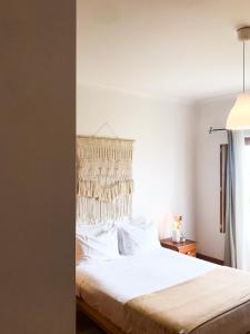 a bedroom with a bed with white sheets and a window at Quinta Amarela - B&B in Nazaré
