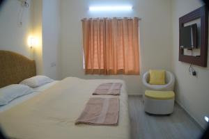 um quarto com uma cama, uma cadeira e uma televisão em Hotel Sunrise em Kanyakumari