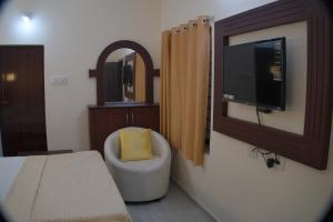 um quarto com uma almofada amarela sentada numa cadeira em Hotel Sunrise em Kanyakumari