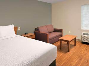 a hotel room with a bed and a chair at WoodSpring Suites Louisville Clarksville in Clarksville