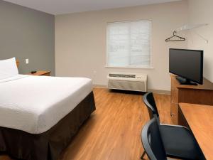 a bedroom with a bed and a desk with a computer at WoodSpring Suites Louisville Clarksville in Clarksville